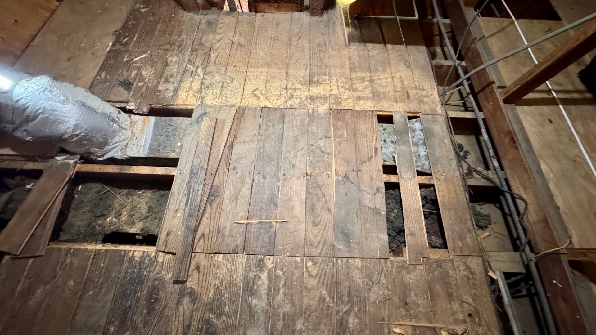 Metal duct beneath attic decking with evidence of substantial wetting.